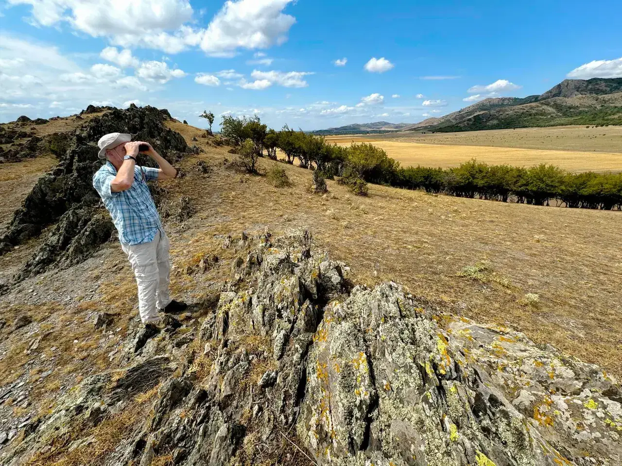 Birdwatcher scanning the rocky steppe landscape of the Măcin Mountains, Dobrogea — oldest mountains in Romania