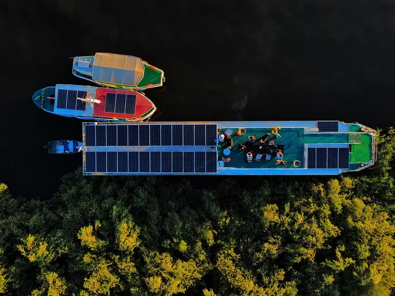 Hotel plutitor Ibis Tours navigând pe canalele Delta Dunării — peisaj cu stuf și nuferi