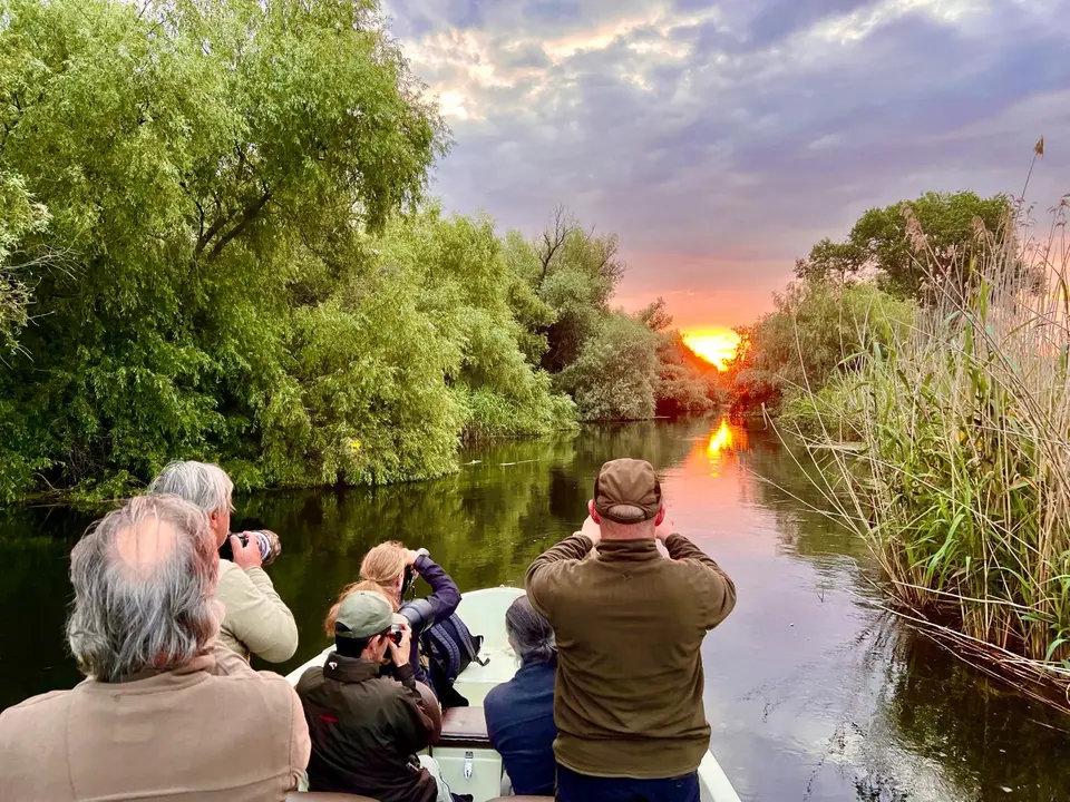Boat trip at sunset through a narrow Danube Delta canal
