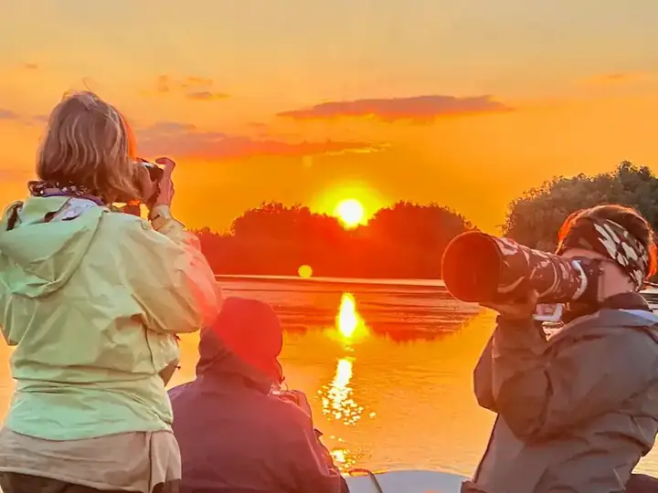 Wildlife photographers shooting from boat at sunset in the Danube Delta
